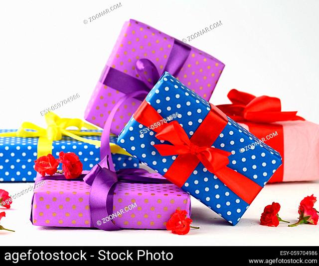 boxes are packed in holiday paper with polka dots and tied with a silk ribbon on a background, birthday gift, surprise, close up
