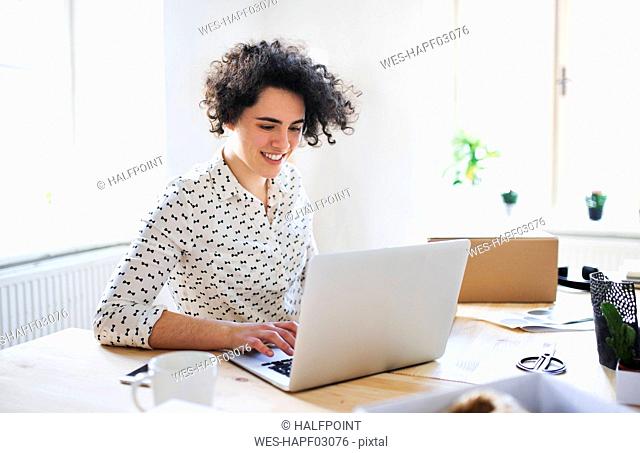 Smiling young woman working on laptop at desk