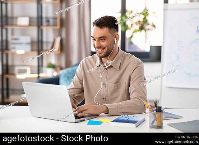 teacher with laptop and earphones working at home