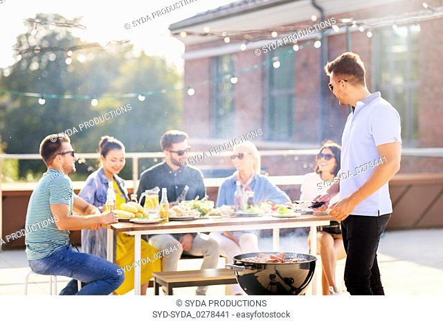 man grilling meat on bbq at rooftop party