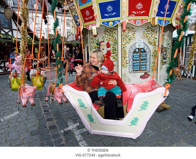middelaged woman with a baby child sitting in a merry-go-round for little kids. - 30/11/2007