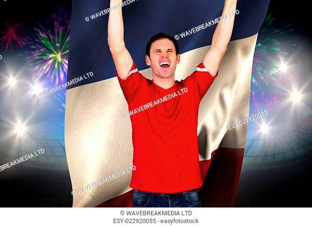 Cheering football fan in red against fireworks exploding over football stadium and france flag