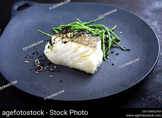 Gourmet fried Japanese skrei cod fish filet with glasswort and furikake as closeup on a modern design plate