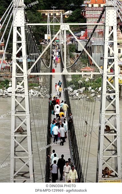 People from across the Lakshman jhula situated over Ganga River at Rishikesh  ;  Uttaranchal ; India