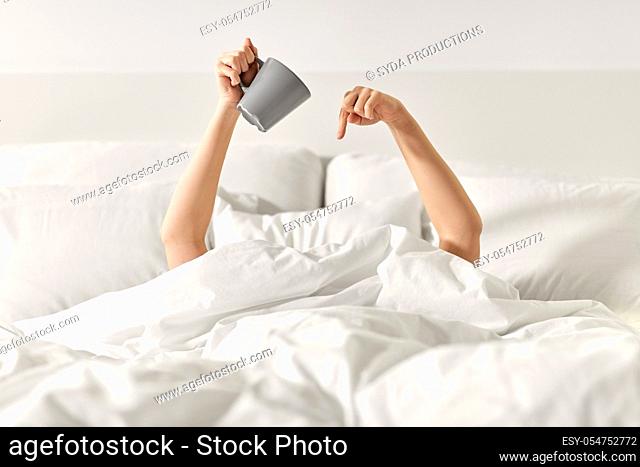 woman with cup of coffee lying in bed