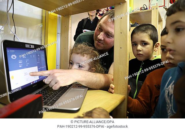 12 February 2019, North Rhine-Westphalia, Aachen: The educator Guido Thissen looks with children at a computer with weather news