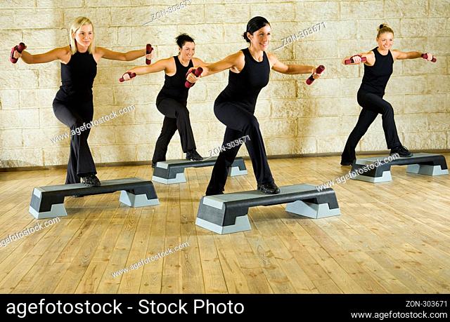 A group of women exercising with dumbbells in the fitness club. Front view