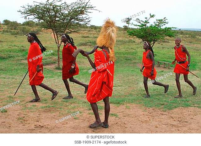 Maasai warriors perform a welcome dance in the Masai Mara Kenya East Africa The Chief wears a traditional lions-mane headress