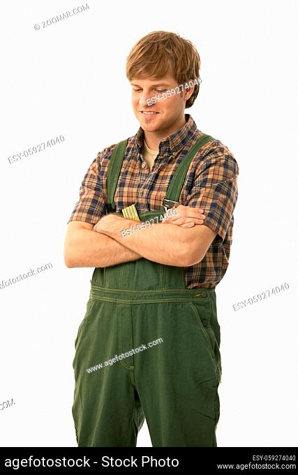 Young handyman wearing green workwear, standing arms crossed, looking down. Isolated on white