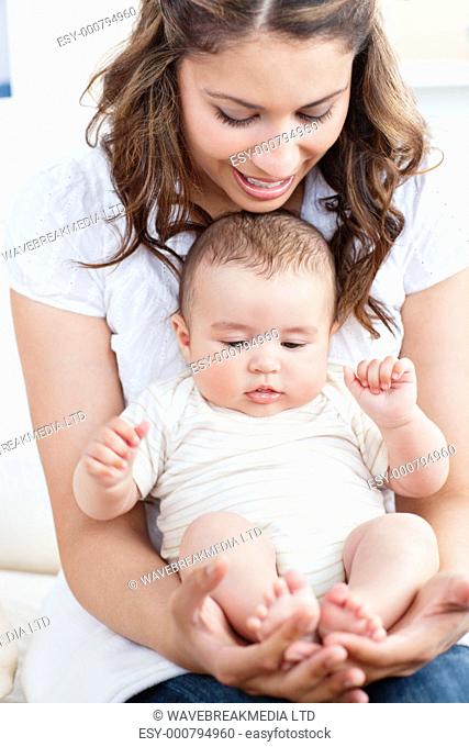 Pretty young mother taking care of her adorable baby at home
