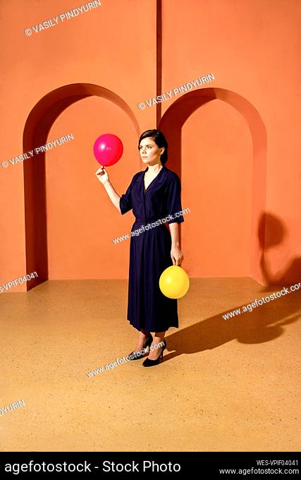 Woman holding balloons in front of wall with arches