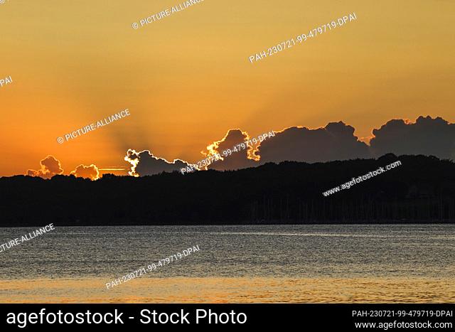 21 July 2023, Schleswig-Holstein, Kiel: The sun rises behind clouds on the eastern shore of Kiel. Photo: Frank Molter/dpa