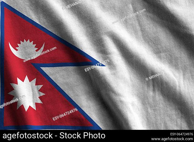 Nepal flag with big folds waving close up under the studio light indoors. The official symbols and colors in fabric banner