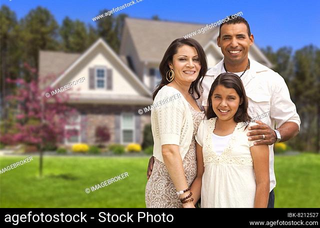 Happy hispanic mother, father and daughter in front of their home