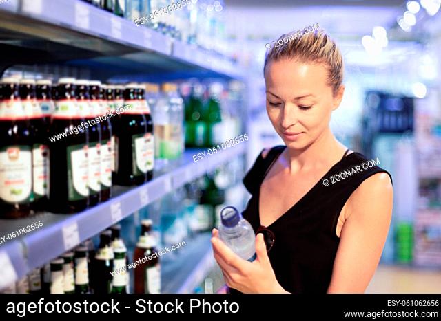 Woman choosing mineral water in grocery store