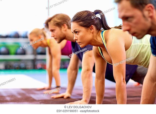 fitness, sport, exercising and people concept - woman doing straight arm plank at group training in gym