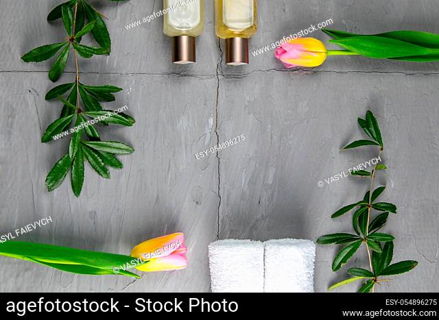 Jewelry, bracelet with keychain and gold earrings together with tulips and green laid on a concrete background. Inside the composition, free space