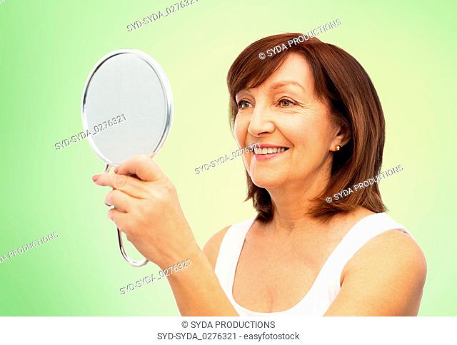 portrait of smiling senior woman with mirror