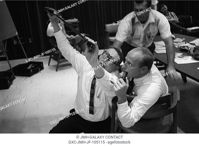 Astronauts Charles Conrad Jr. (with pipe) and Richard F. Gordon (background) view negatives from their Gemini 11 mission