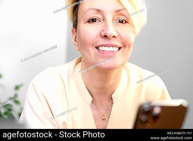 Smiling woman with mobile phone at home