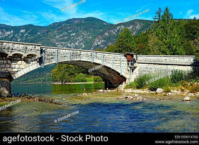 The old bridge over the lake against the background of mountains