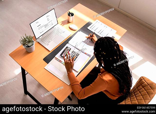 High angle portrait of businesswoman calculating tax at desk in office