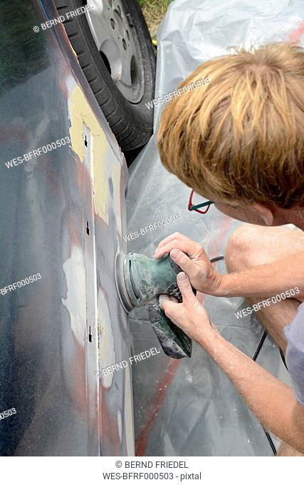 Germany, Zeuthen, Man mending car paint