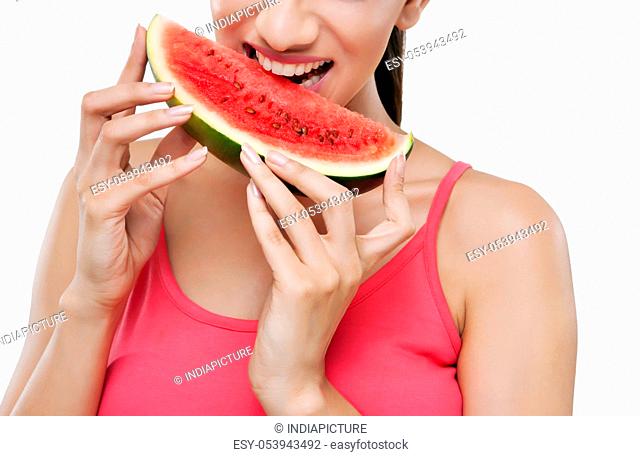 Midsection of young woman taking a bite from slice of watermelon
