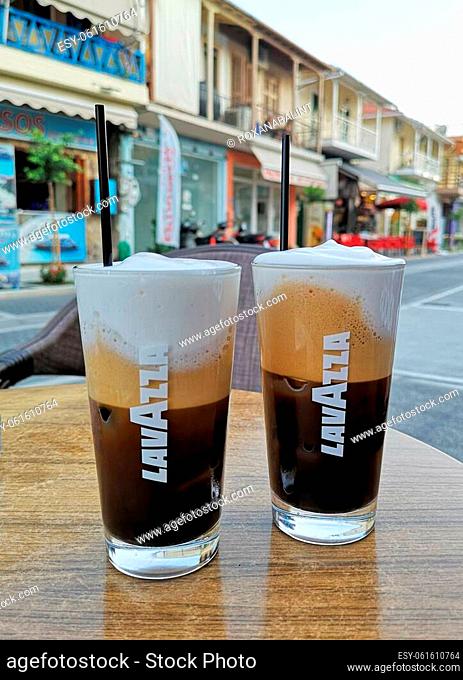 LEFKADA, GREECE - AUGUST 24, 2021: Two glass cup of branded iced coffee from Lavazza along traditional greek street in Lefkada, Greece