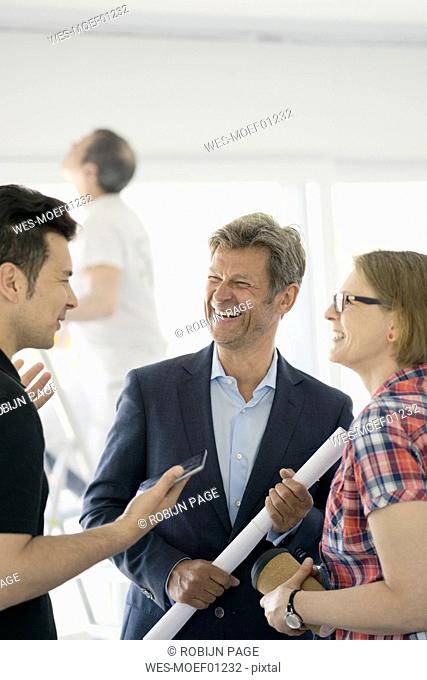 Happy man in suit and couple talking in unfinished building