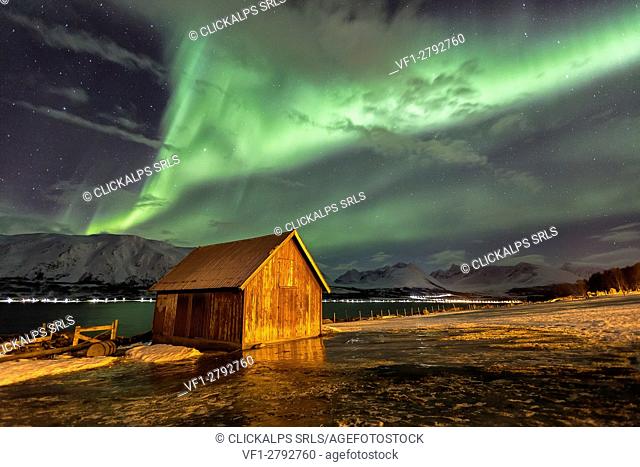 Northern Lights illuminates the wooden cabin at Lenangsoyra Lyngen Alps Tromsø Lapland Norway Europe