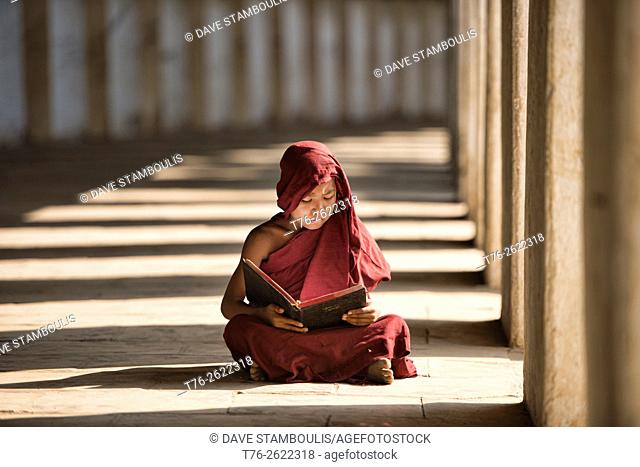 A young monk reading with rays of sunlight in the temples of Bagan, Myanmar