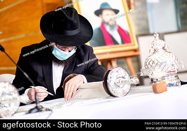 13 April 2021, Lower Saxony, Hanover: Arie Merkhasin, a specially trained Torah scribe, also called a sofer, writes on a new Torah before the opening of the new...