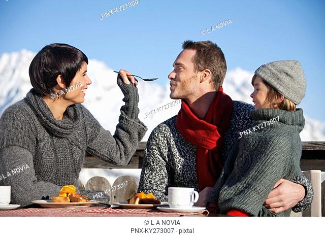 Couple and daughter eating on balcony at ski resort