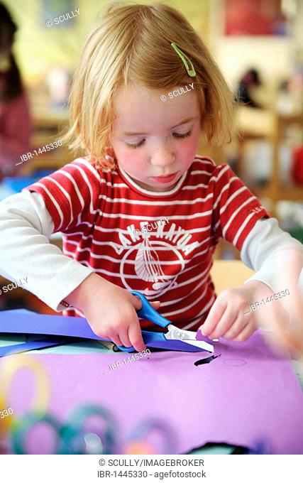 Red-haired girl doing craft in a kindergarten