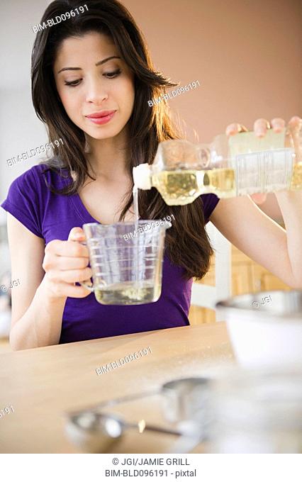 Mixed race woman measuring cooking oil