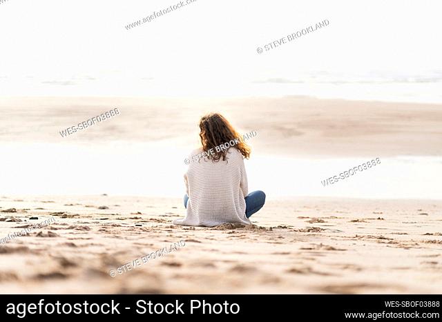 Woman looking at view while sitting on sand during vacations