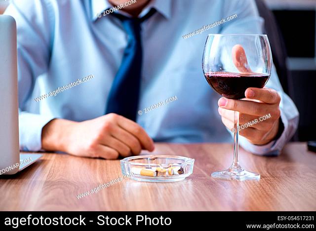 The male employee drinking alcohol and smoking cigarettes at workpla