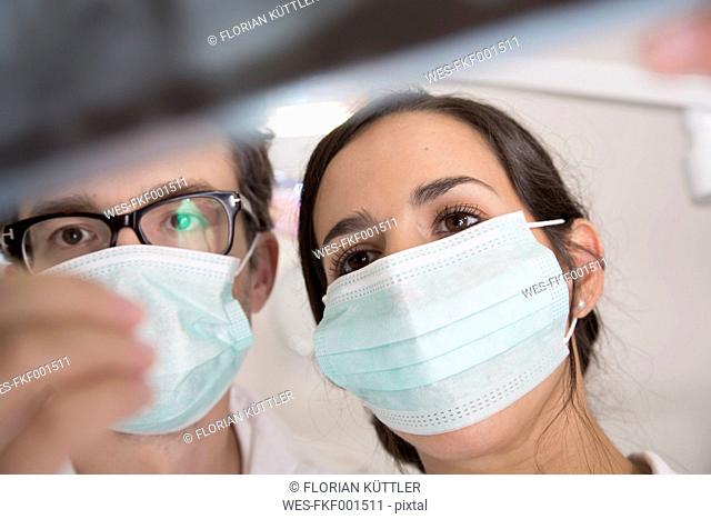 Two doctors with mouth masks looking at x-ray image
