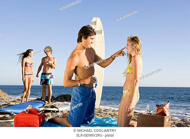Young man applying sun lotion to girlfriend