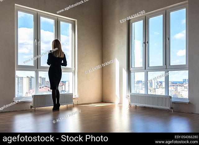 A girl looks into large stained glass windows in an empty apartment