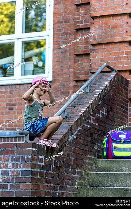Blond girl sitting with school bag on bannister, Kiel, Schleswig-Holstein, Germany, Europe