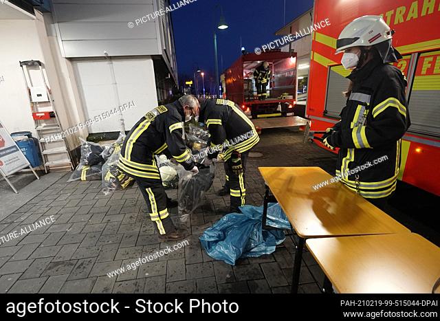 19 February 2021, Hessen, Limburg: Firefighters pack their turnout gear in special plastic bags after an operation at Limburg Hospital