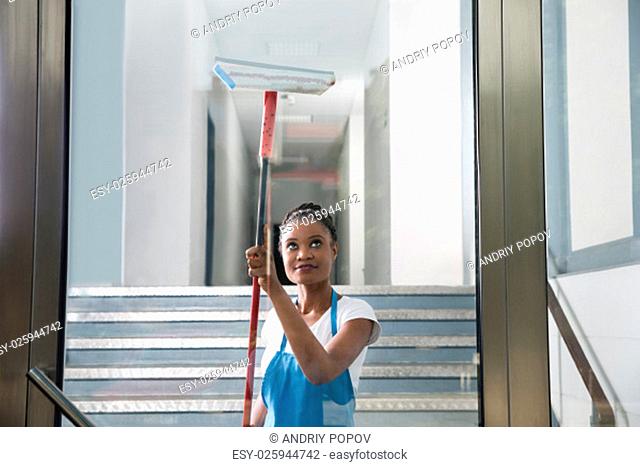 African Woman Cleaning Glass With Rubber Window Cleaner