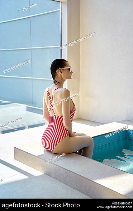 Young woman wearing swimwear sitting with feet in hot tub at spa