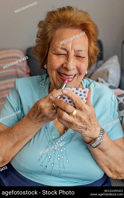 Happy senior woman applying lipstick