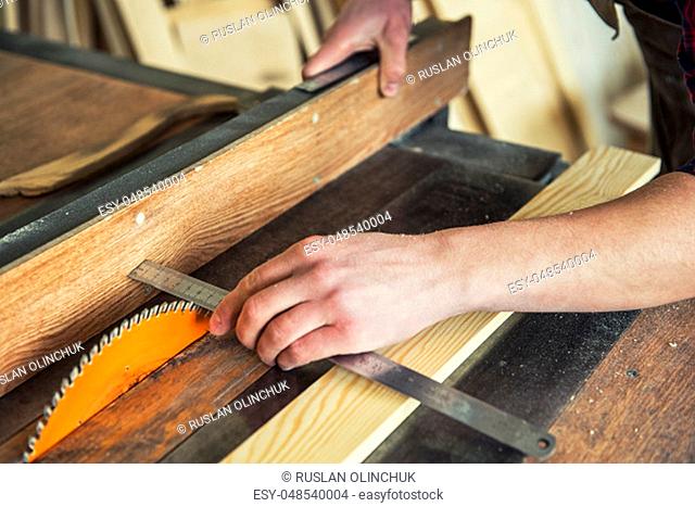 Construction worker cutting wooden board with circular saw