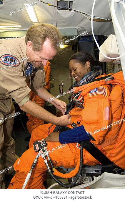 Astronaut Joan E. Higginbotham, STS-116 mission specialist, gets help with the final touches on her training version of a shuttle launch and entry suit prior to...