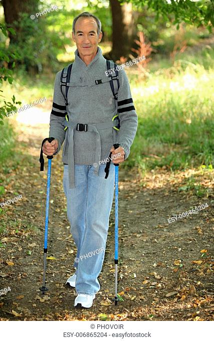 senior gentleman in forest with rambler walking poles
