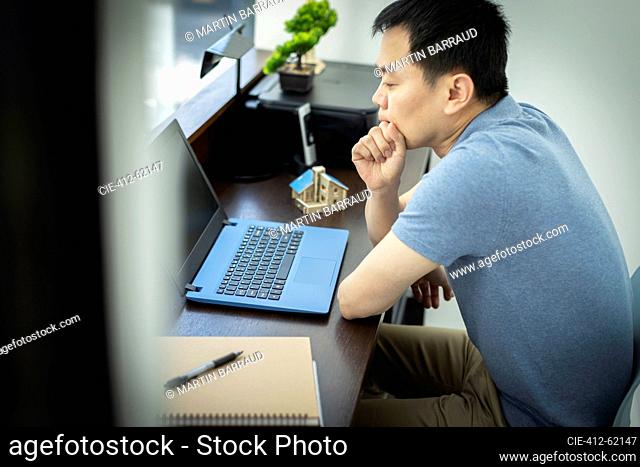 Thoughtful male engineer working at laptop in office